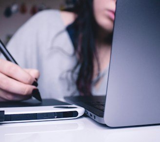 woman using drawing pad while sitting in front of laptop